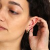 Model wearing Mustard Cloisonné Huggie Hoop Earrings in Gold with hand behind ear