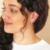 Model looking to side wearing Mustard Cloisonné Huggie Hoop Earrings in Gold with curated ear look