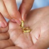 Model holding Mustard Cloisonné Huggie Hoop Earrings in Gold in palm of hand