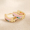 Pink Enamel and Crystal Huggie Hoop Earrings in Gold on beige coloured fabric