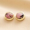 Close up of vintage-inspired Pink Semi-Precious Stone Stud Earrings in Gold on beige fabric