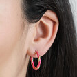 Close Up of Pink Twisted Enamel Hoop Earrings in Gold on Model