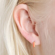 Close up of Red Enamel Scalloped Huggie Hoop Earrings in Gold on model