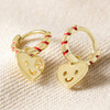 Red and Gold Heart Face Huggie Hoop Earrings on Neutral Coloured Fabric