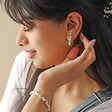 White Cloisonné Hoop Earrings in Gold on Model with Hand Behind Ear Looking to Side