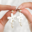 Model Holding White Enamel and Pearl Daisy Drop Earrings in Gold