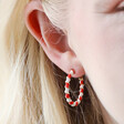 Close Up of Red and White Twisted Enamel Hoops in Gold on Model