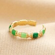 Closeup of Green Enamel Adjustable Ring in Gold on Beige Ribbed Fabric