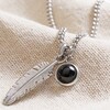 Close Up of Men's Feather and Semi-Precious Stone Pendant Necklace on Neutral Coloured Fabric