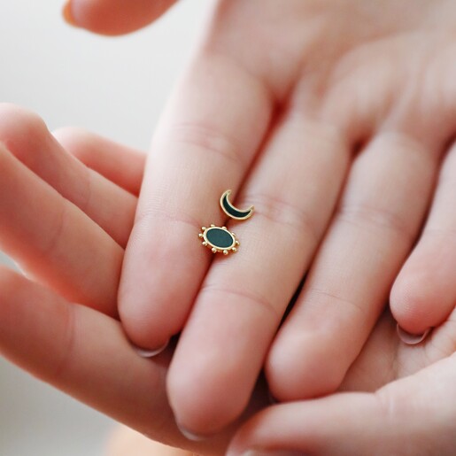 Model Holding Navy Enamel Mismatched Sun and Moon Stud Earrings in Gold in Between Fingers