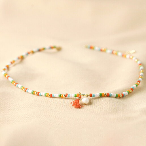 Colourful Pearl and Tassel Beaded Necklace in Gold on beige coloured fabric