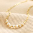Close Up of Freshwater Pearl Chain Necklace in Gold on Beige Fabric
