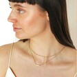 Model looking to side wearing curated look with Gold Stainless Steel Pink Aventurine Half Circle Pendant Necklace