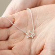 Model Holding Mixed Metal Crystal Double Star Pendant Necklace in Silver in Palm of Hand