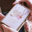 Close Up of Hands Holding Mother & Child Set of 2 Heart Puzzle Necklaces in Silver and Rose Gold Box Packaging