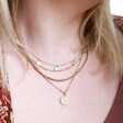 Model Wearing Mother & Child Sun Necklace in Gold Layered With Other Necklaces