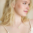 Model looking to side wearing Dove Charm Pearl Beaded Necklace in Gold