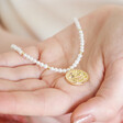 Model holding Dove Charm Pearl Beaded Necklace in Gold in palm of hand
