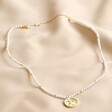Dove Charm Pearl Beaded Necklace in Gold on beige coloured fabric
