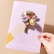 Model Holding Blooming Gorgeous Dried Flower Greetings Card Against Beige Coloured Background