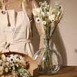 Model Standing Behind Natural Market Style Dried Flower Bouquet in Vase and in Paper