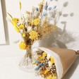 Yellow and Blue Dried Flower Bouquet Inside Vase Beside Wrapped Bouquet