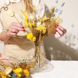 Model Arranging Yellow and Blue Dried Flower Bouquet in Glass Vase