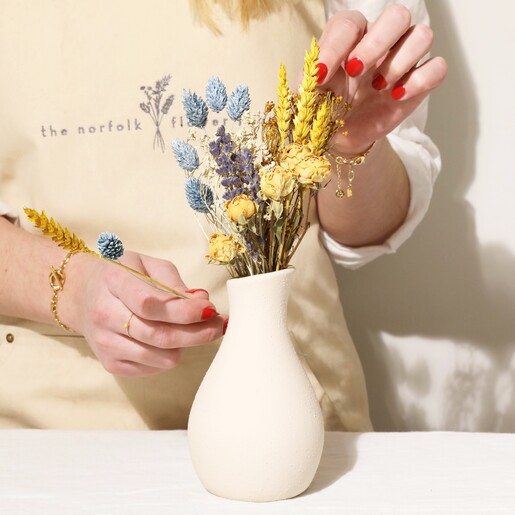 Model Arranging Yellow and Blue Dried Flower Posy in Cream Vase