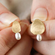 Model Holding Mismatched Pearl and Organic Shape Stud Earrings