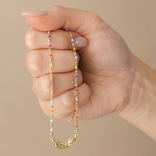 Model Holding Rainbow Beaded Feather Charm Necklace in Gold