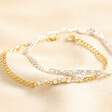 Crystal and Pearl Bar Bracelet in Gold with silver version stacked on top sat above beige fabric