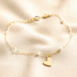 Beaded Pearl Heart Charm Bracelet in Gold on Beige Fabric