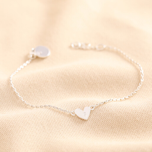 Personalised Initial Shiny Heart Charm Bracelet in silver against neutral coloured material