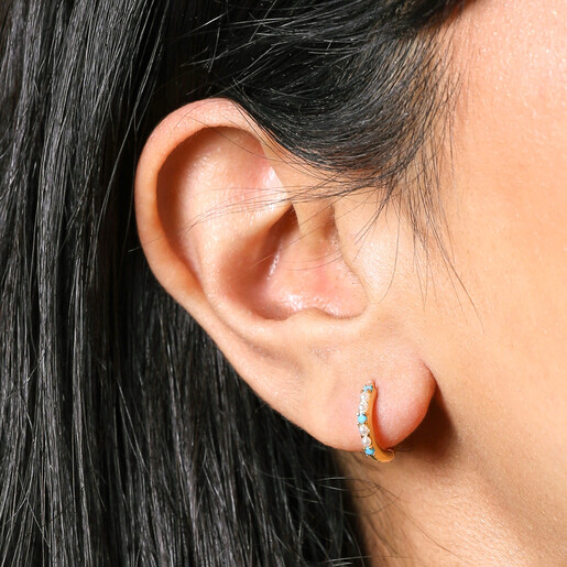 Close up of Blue Stone and Pearl Huggie Hoop Earrings in Gold on model