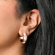 Close up of Chunky Oval Pearl Hoop Earrings in Gold on model
