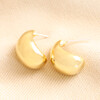 Chunky Teardrop Half Hoop Earrings in Gold on beige fabric