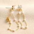 Side of Crystal Flower and Pearl Chain Stud Earrings in Gold on Beige Fabric