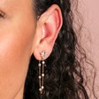 Zoomed in Close Up of Crystal Flower and Pearl Chain Stud Earrings in Gold on Model
