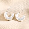 Small Crystal Hammered Half Hoop Earrings in Silver against beige coloured fabric