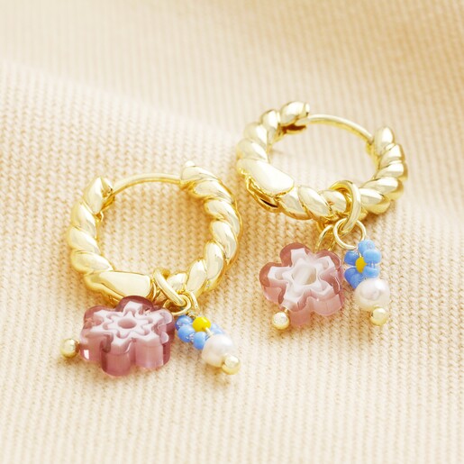 Millefiori Flower Bead Twisted Drop Huggie Hoop Earrings in Gold Millefiori Flower Bead Twisted Drop Huggie Hoop Earrings in Gold on top of beige coloured fabric