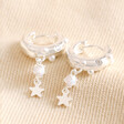 Pearl and Crystal Star Charm Huggie Hoop Earrings in Silver on top of neutral coloured fabric