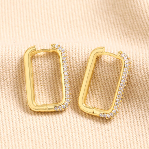 Rectangular Crystal Huggie Hoop Earrings in Gold  Rectangular Crystal Huggie Hoop Earrings in Gold on Beige Fabric