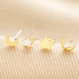 Set of Four Hamsa Hand, Moon and Star Stud Earrings in Gold on Beige Fabric