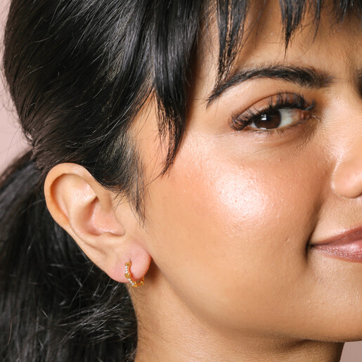 Earrings on Model Tiny Heart and Crystal Huggie Hoop Earrings in Gold on Model