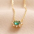 Green Crystal Pendant Necklace in Gold on Beige Fabric