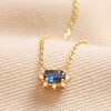 Blue Crystal Pendant Necklace in Gold on beige Fabric