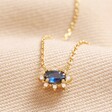 Blue Crystal Pendant Necklace in Gold on beige Fabric