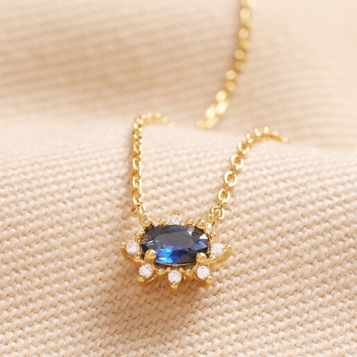 Blue Crystal Pendant Necklace in Gold Blue Crystal Pendant Necklace in Gold on beige Fabric