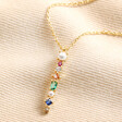 Colourful Gemstone Bar Pendant Necklace in Gold laying on top of beige coloured fabric