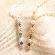 Close up of Colourful Gemstone Bar Pendant Necklace in Silver and gold on top of beige fabric
